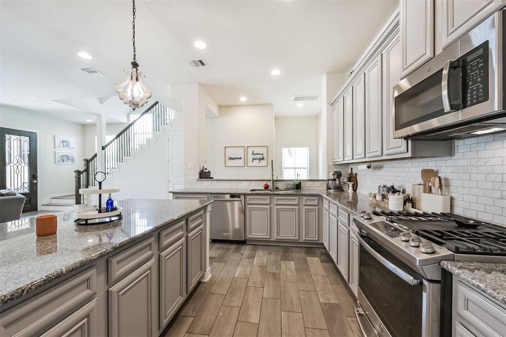 Chef's eat-in island kitchen features an abundance of cabinets, lengthy granite countertops and stainless steel appliances