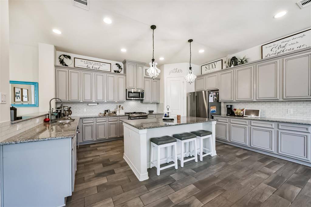 Chef's eat-in island kitchen features an abundance of cabinets, lengthy granite countertops and stainless steel appliances
