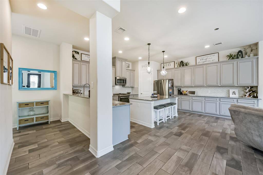 Chef's eat-in island kitchen features an abundance of cabinets, lengthy granite countertops and stainless steel appliances