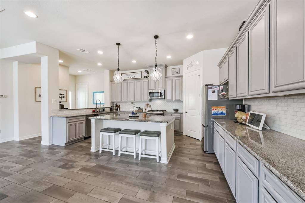 Chef's eat-in island kitchen features an abundance of cabinets, lengthy granite countertops and stainless steel appliances