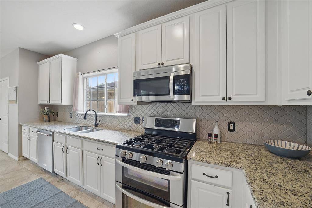 The beautiful stainless steel gas range has double ovens and a built-in microwave above.