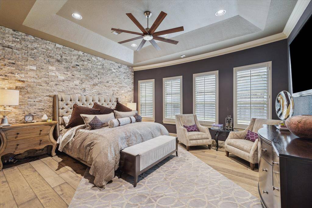 Alluring primary suite featuring stacked stone accent wall & designer paint.