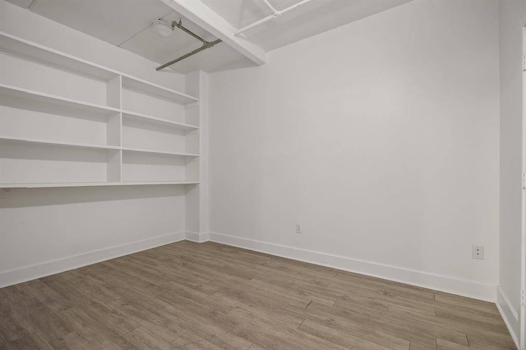 3rd bedroom with wall of shelving and laminate flooring.