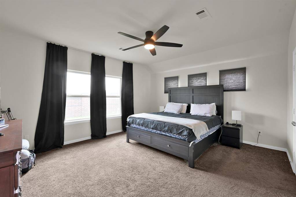 Primary bedroom suite with ceiling fan and large windows for natural light.
