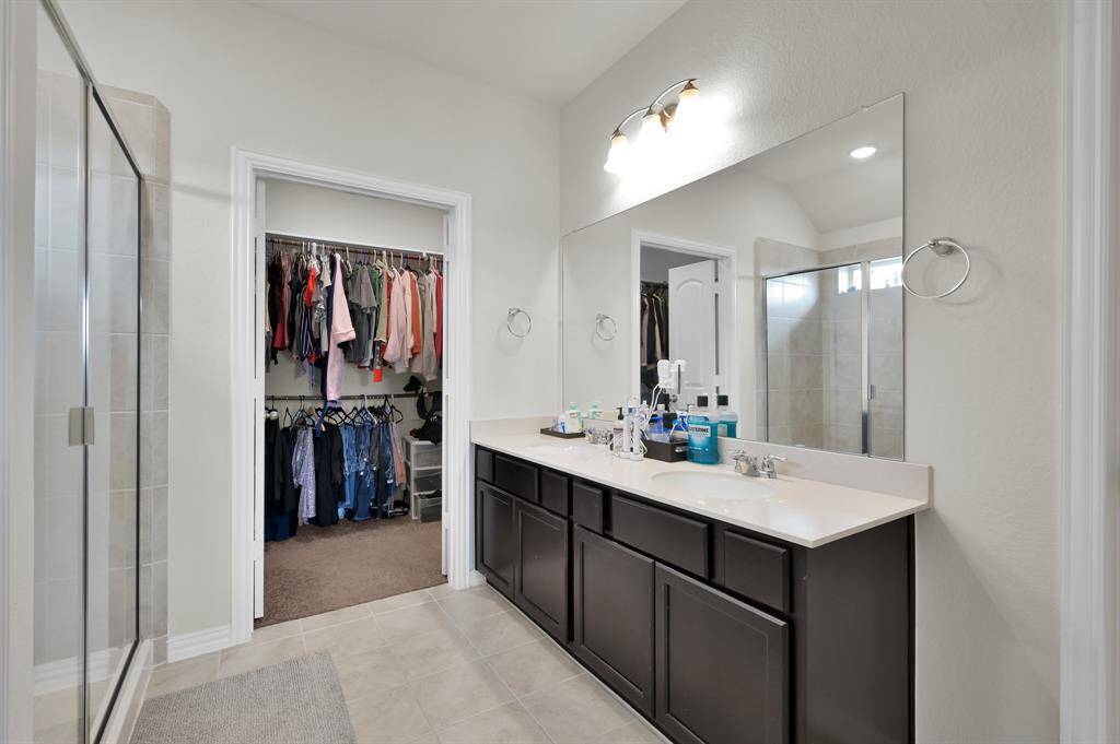 Primary ensuite bathroom featuring dual vanities and walk-in shower.