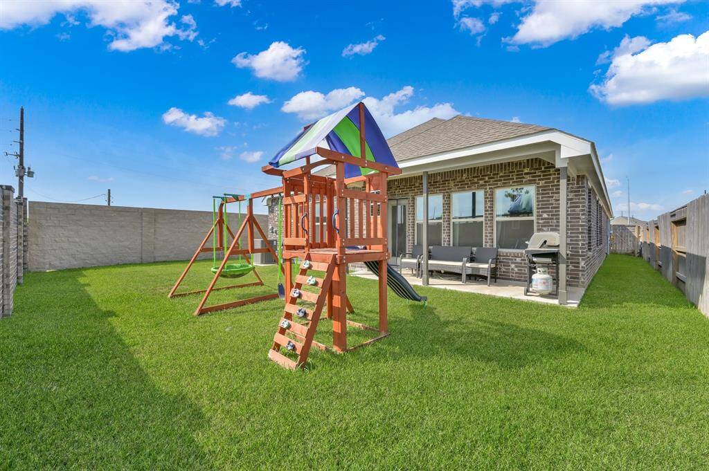 Rear view of the home showing the covered patio and beautifully maintained yard.