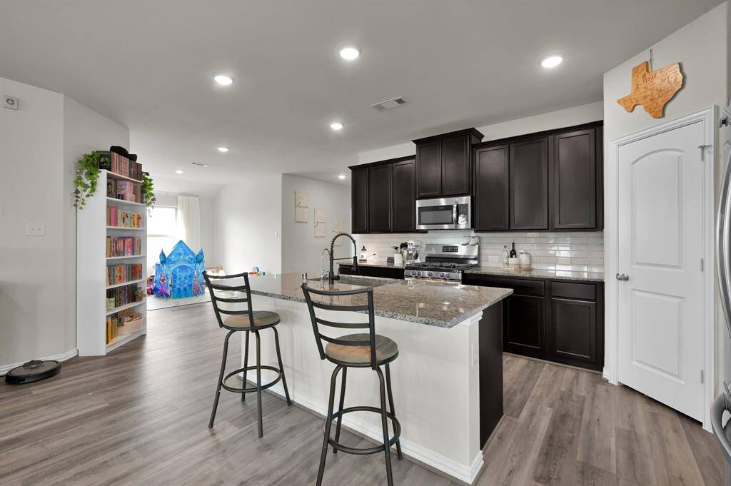 Modern kitchen with upgraded backsplash, island seating, and stainless steel appliances.