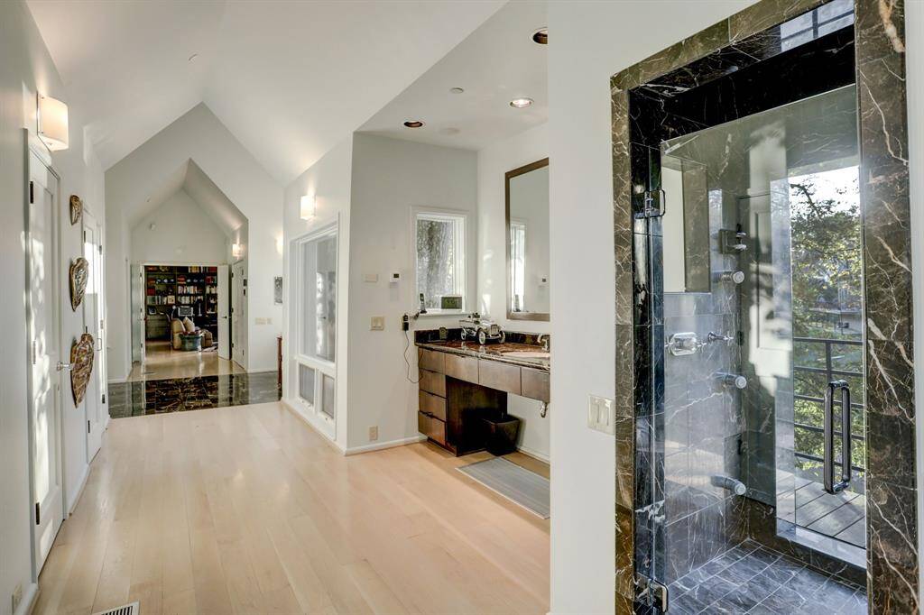 This luxurious shower is a marble-clad oasis, featuring elegant glass doors and a window that offers stunning views of the bayou.