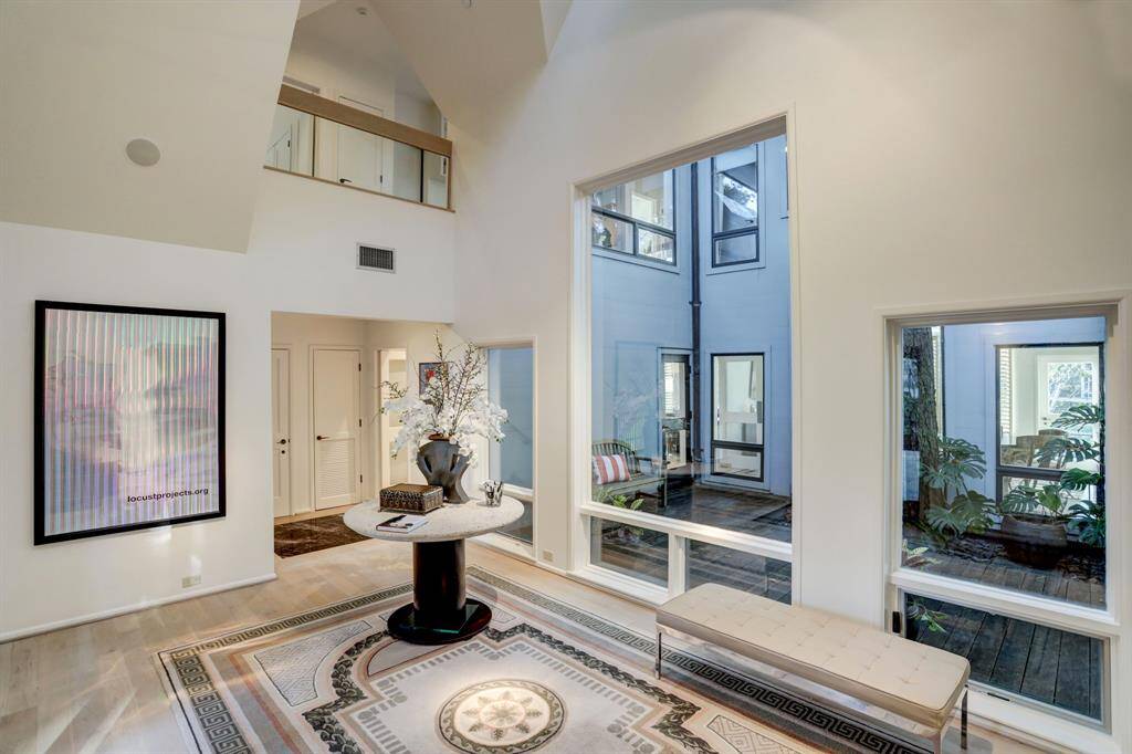 The foyer offers a captivating view of an interior courtyard or atrium through the windows, providing a serene and picturesque backdrop that elevates the space to a tranquil retreat.