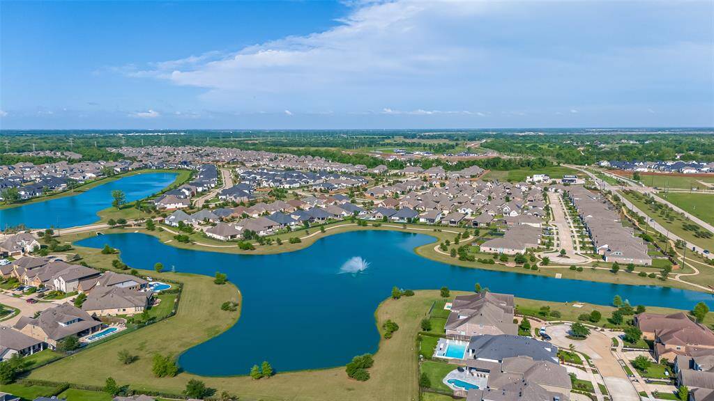 This aerial photo showcases a serene residential community with well-maintained homes, lush greenery, and scenic water features, creating a peaceful suburban atmosphere.