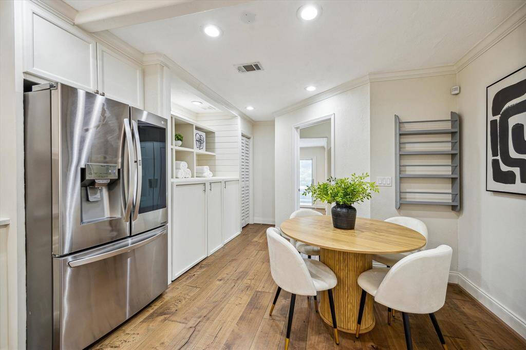 Tucked just off the kitchen, this cozy dining nook features built-in cabinetry that discreetly houses the washer and dryer—offering hidden functionality without sacrificing style. Recessed lighting, crown molding, and open shelving add charm and versatility to this thoughtfully designed space.