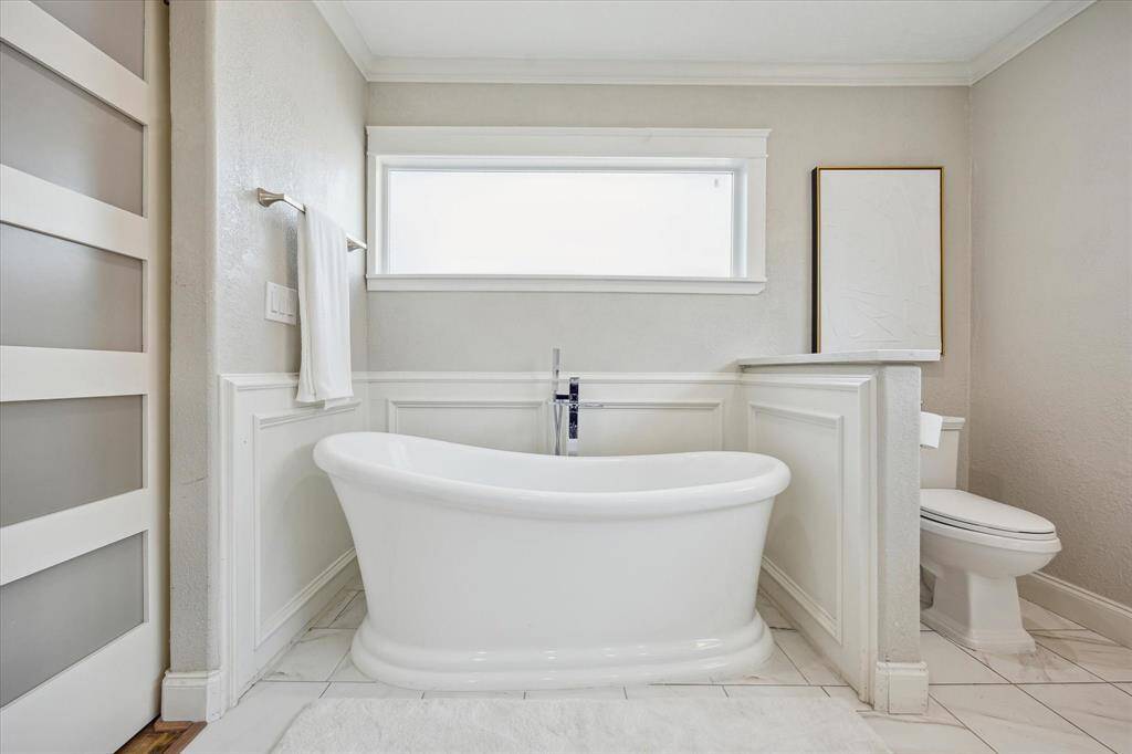 Unwind in style with this sleek freestanding soaking tub, set against classic wainscoting and paired with a contemporary chrome filler—your personal retreat for ultimate relaxation.