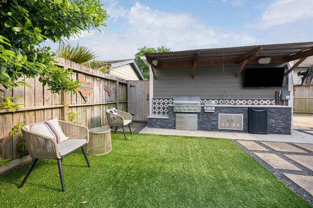 Host unforgettable gatherings in this entertainer’s dream yard with a fully equipped outdoor kitchen, complete with a covered grill station, beverage fridge, mounted TV, and bar seating—surrounded by lush landscaping and privacy fencing. Low maintenance turf for a polished look all year long!