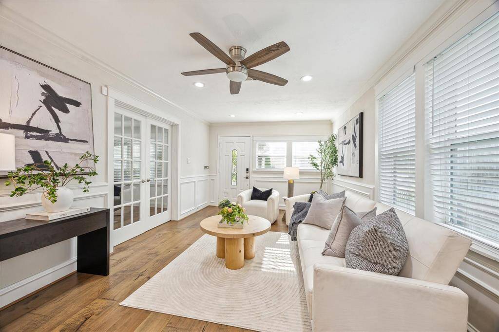 Bright and inviting, the living room is filled with natural light from multiple windows and showcases elegant trim work, warm hardwoods, and timeless wainscoting—creating a comfortable yet sophisticated atmosphere from the moment you step inside.
