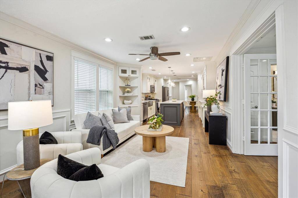 An open-concept living space seamlessly connects to the kitchen and dining area, featuring wide-plank hardwood floors, crown molding, recessed lighting, and custom built-ins that enhance both function and style.
