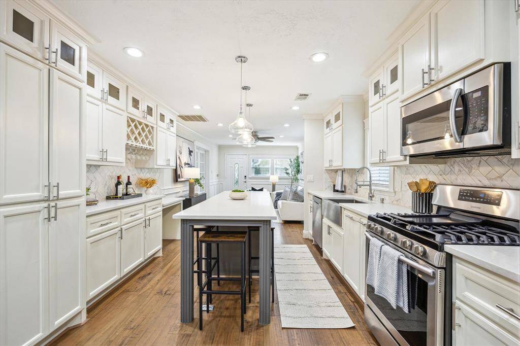 Enjoy chef-inspired cooking with stainless steel appliances, a deep farmhouse sink, quartz countertops, and a stylish herringbone tile backsplash—all thoughtfully laid out for function and flow into the open living space.