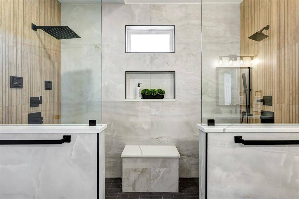 This impressive curb-less shower is a true showstopper, featuring teak wood-look tile from floor to ceiling and large-format porcelain tiles for a sleek, modern finish. Thoughtfully designed with three recessed shampoo niches, a built-in bench, four body sprays, a handheld shower, and a luxurious rain shower head, this one-of-a-kind space brings spa-level comfort home.