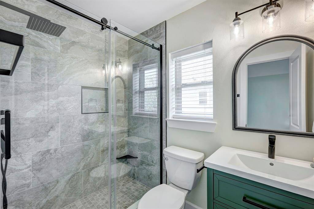 This en-suite bathroom for the second bedroom has a frameless treated glass shower, handheld and rain shower head with recessed shampoo niche.