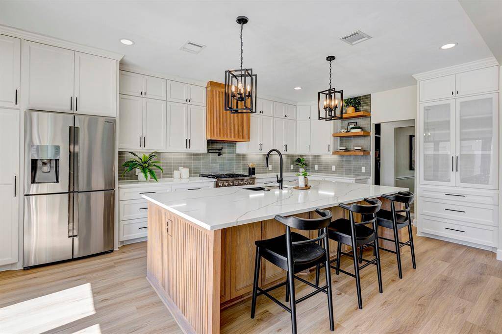 This stunning 10-foot white oak island offers generous storage on both sides and features hidden electrical outlets seamlessly integrated into the decorative end caps—mirroring the design of the custom bespoke vent hood for a cohesive, elevated look.