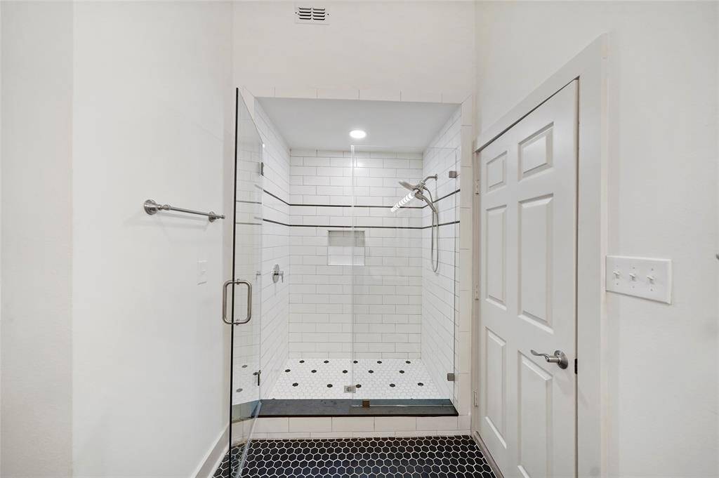 Relaxing walk-in shower with white tile and glass doors.