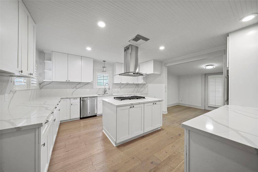 Spacious kitchen with white cabinets and counter tops, and chrome appliances.