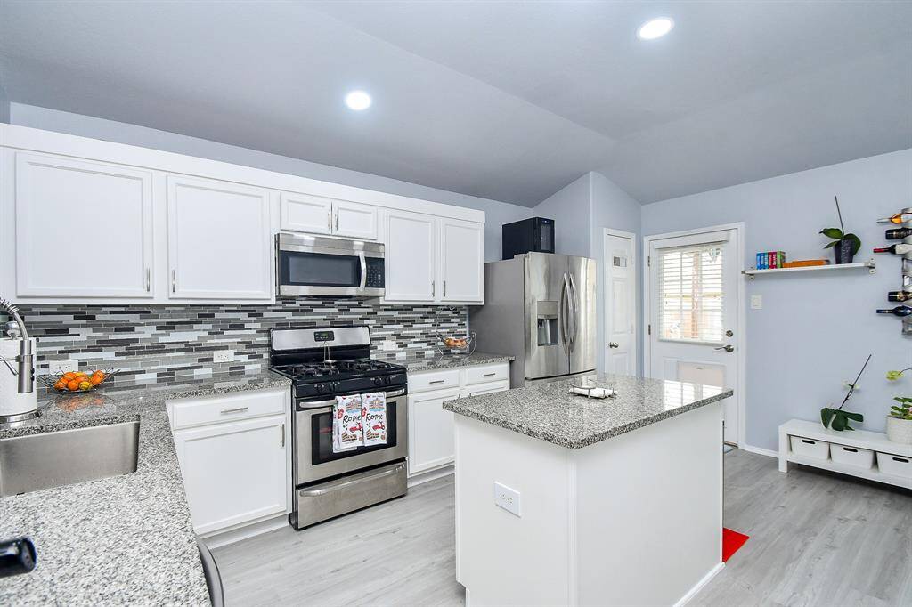 There's just something about a primarily white kitchen (or bathroom, for that matter) that instantly soothes us! Subtle granite counter tops are visually complemented by sleek, mosaic-like tile backsplash with durable, easy care tile/laminate flooring.