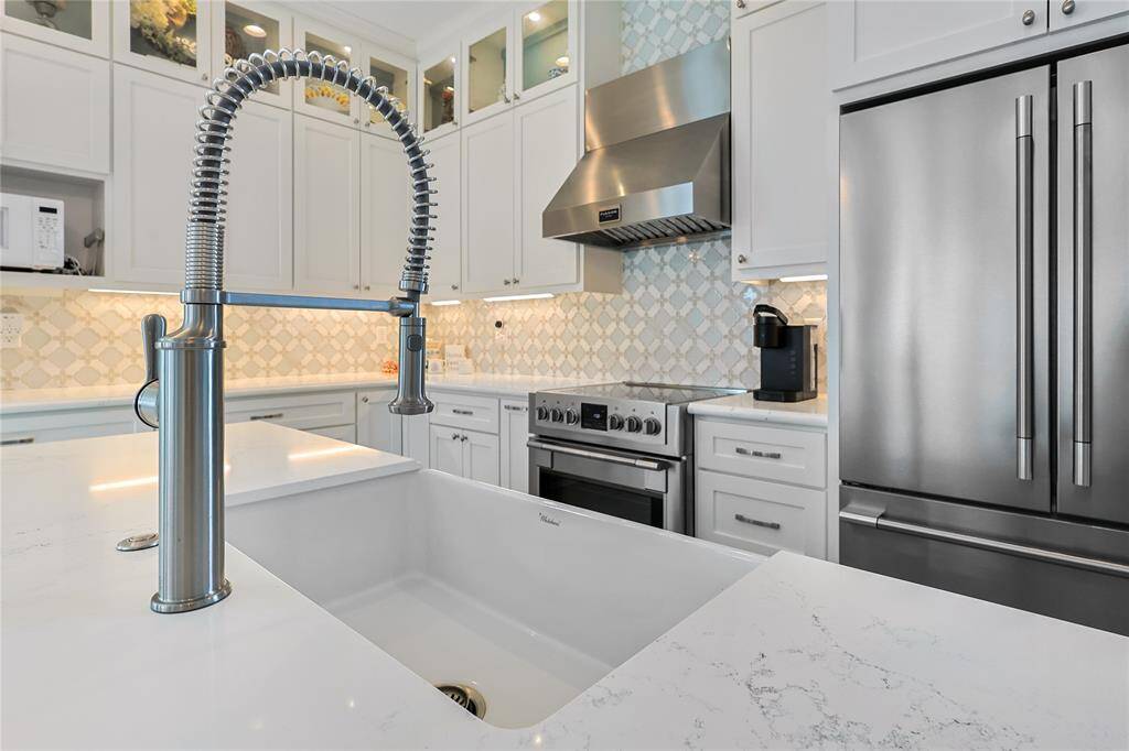 The gourmet kitchen is equipped with a premium Whitehaus sink and a sleek, professional-grade spring coil faucet, combining style and functionality. Beautiful designer fixtures elevate the space, ensuring elegance without missing a view.