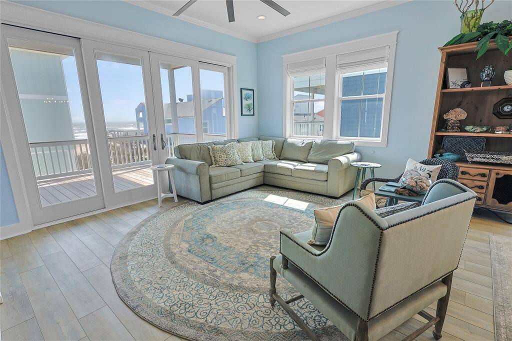 The spacious living room is designed for comfort and style, featuring durable Neuma sliding glass storm doors that invite natural light while offering stunning Gulf views. A high-performance BAF fan enhances airflow, creating a cool and inviting atmosphere.