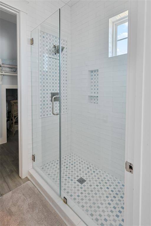 The first-floor primary ensuite exudes luxury with exquisite designer tile work and sleek modern fixtures, creating a sophisticated spa-like retreat for ultimate relaxation.