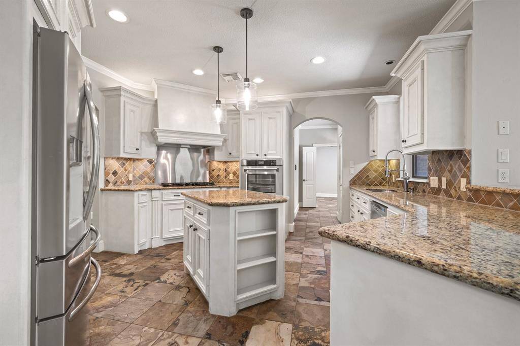 The light brown granite countertops beautifully complement the rich tone of the slate flooring, while the ceramic backsplash adds the cherry on top for creating a warm and spacious kitchen that's a true culinary retreat.