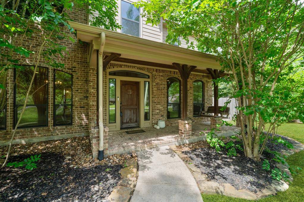 The front porch is spacious and inviting. The charming wooden swing and arched brick accents are perfectly shaded by the trees, offering a peaceful spot to relax and enjoy the view.