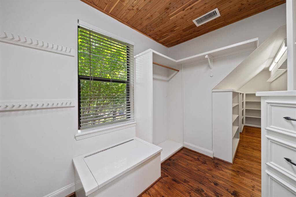 This walk-in closet features custom built-ins, abundant shelving, and a charming wood-paneled ceiling. Organization meets style and function all overlooking the trees for natural serenity.