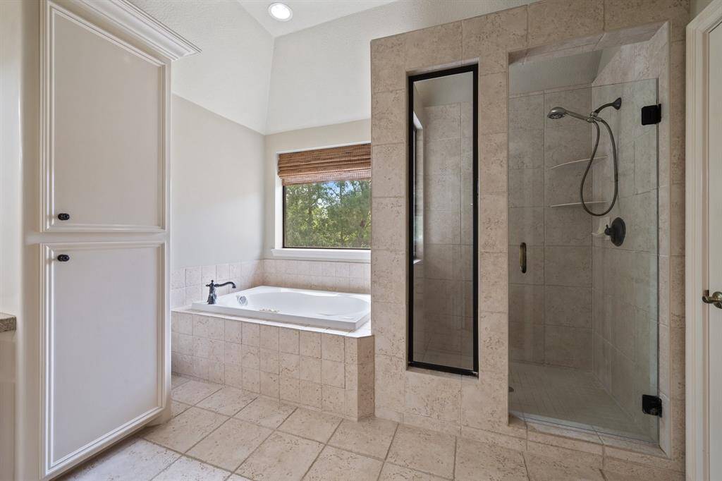 This serene bathroom retreat boasts a classic white bathtub framed by light brown tiles and a small window that overlooks the tree canopy of the home. The refined design of the faucet shines with elegance. Such a peaceful and beautiful relaxation nook!