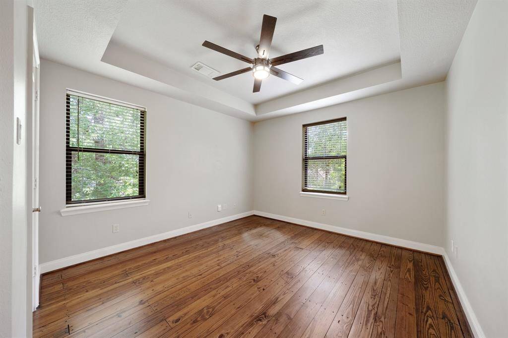 The dark wood fan, along with the windows, helps provide a refreshing airflow and adds a touch of warmth and elegance to the room.
