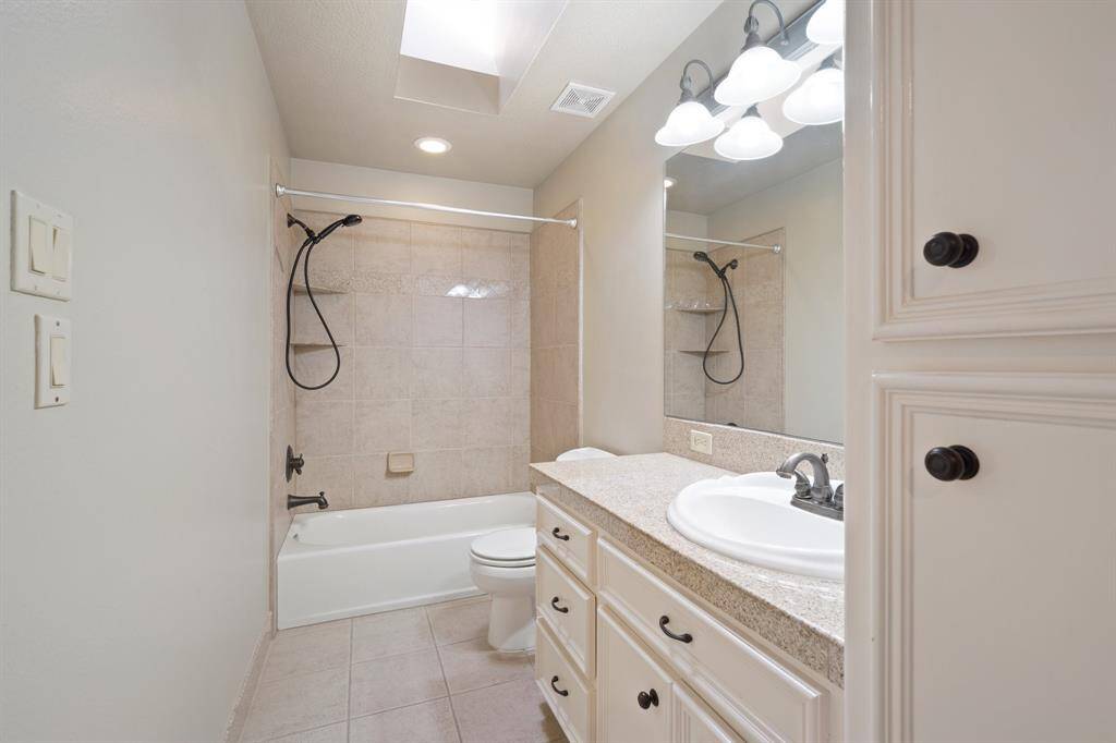 Continuing the home's vintage aesthetic, this bathroom features dark metal fixtures above the wall-mounted mirror, spacious white drawers, and a sleek, minimalist bathtub.