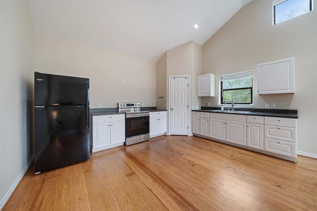 The upstairs apartment above the garage is fully furnished and features a spacious kitchen with white cabinets and a refrigerator.