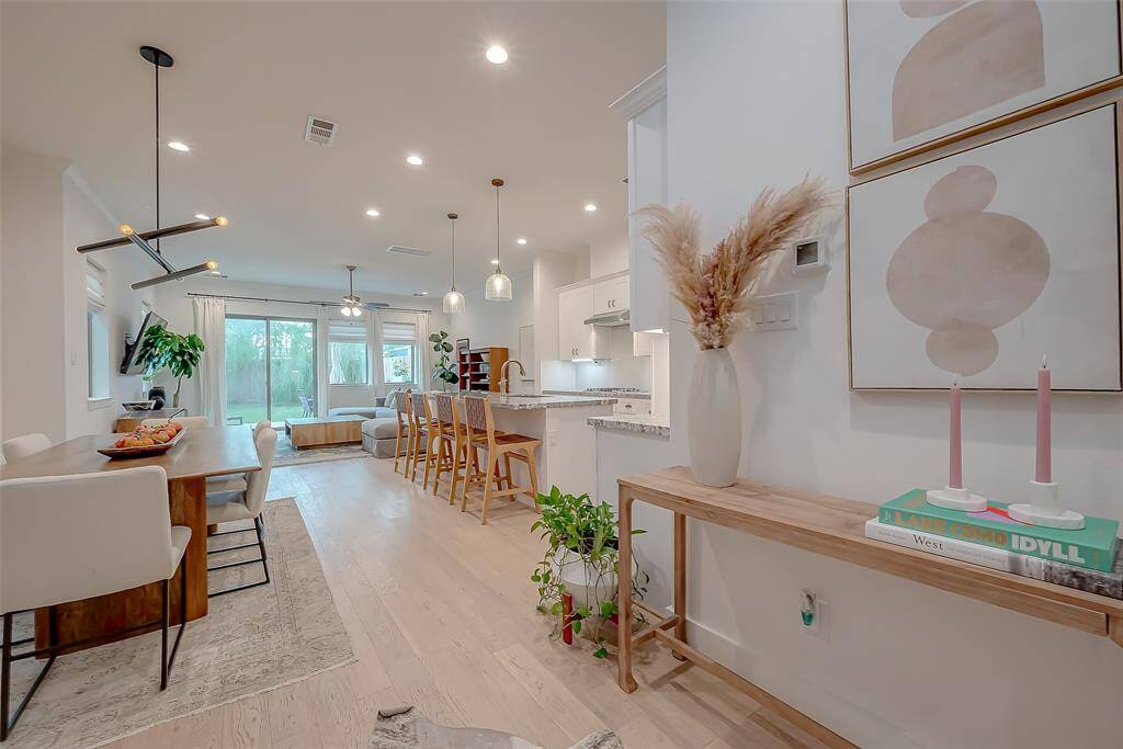 Stunning Ground Floor Living that has access to a Private Large Fenced Back in Yard. This is a modern, open-concept interior featuring a spacious hallway that leads into a combined living and dining area.Lots of natural light illuminates this space, highlighting the light hardwood floors.