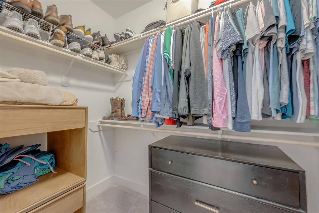This is one of two Primary spacious, well-organized walk-in closet featuring multiple shelves and hanging rods, offering ample storage solutions for clothing and accessories. The neutral color palette ensures it will blend seamlessly with any decor style