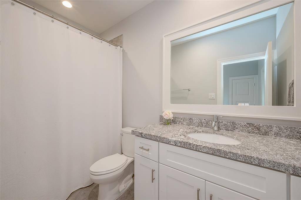 One of 3 Full Bathrooms, this one is on 3rd floor. This bathroom features a modern aesthetic with a granite countertop, white cabinetry, and a large framed mirror. It includes a full bath in neutral color tones and Shower in Tub.