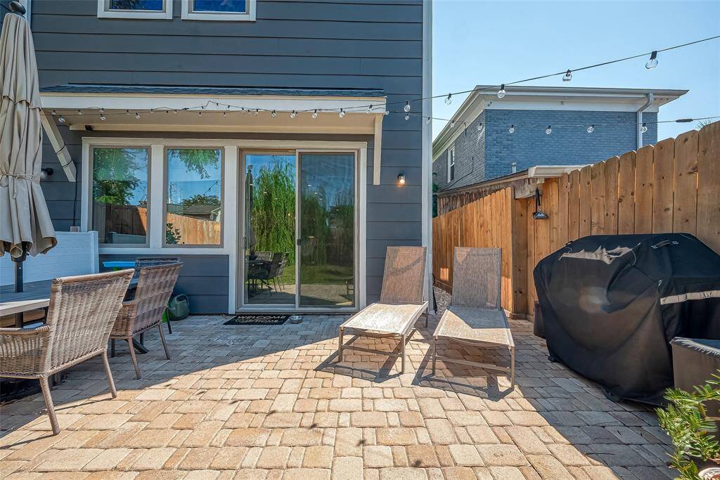 Cozy outdoor patio space featuring paver stone patio. The area is fenced for privacy and has room for a grill. Large glass doors connect the patio to the interior, suggesting a seamless indoor-outdoor living experience.