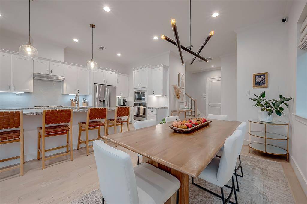 This is a spacious and well-lit kitchen with sleek lines, gorgeous granite countertops dining area adjacent, and a cozy living space, featuring modern lighting, beautiful light hardwood floors, and large windows that provide ample natural light. The open floor plan allows for comfortable living and seamless entertaining.