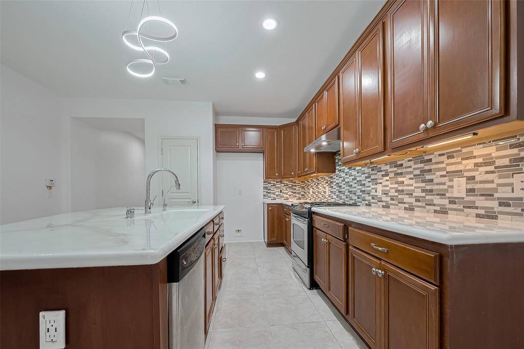 Elegant kitchen with rich cabinetry, modern lighting, and spacious island for cooking and entertaining.