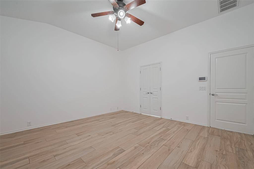 Expansive primary bedroom with elegant wood-look tile flooring.