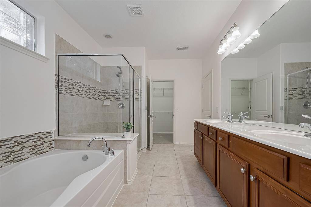 Luxurious en-suite features a spacious soaker tub, a separate shower, and dual vanities for ultimate comfort.