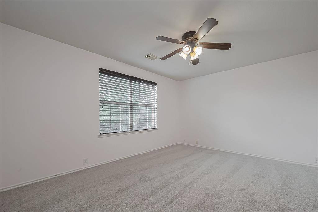 First upstairs bedroom featuring large windows with blinds and an energy-efficient ceiling fan with walk-in closet.