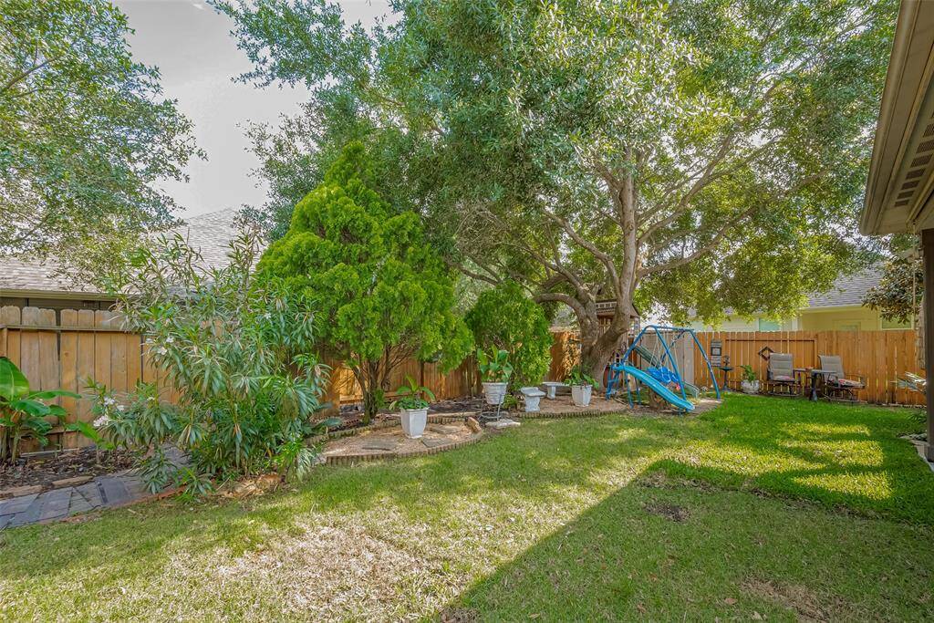 Discover a charming backyard oasis with inviting seating, a delightful playhouse, a convenient storage shed, and a cozy table for morning coffee.