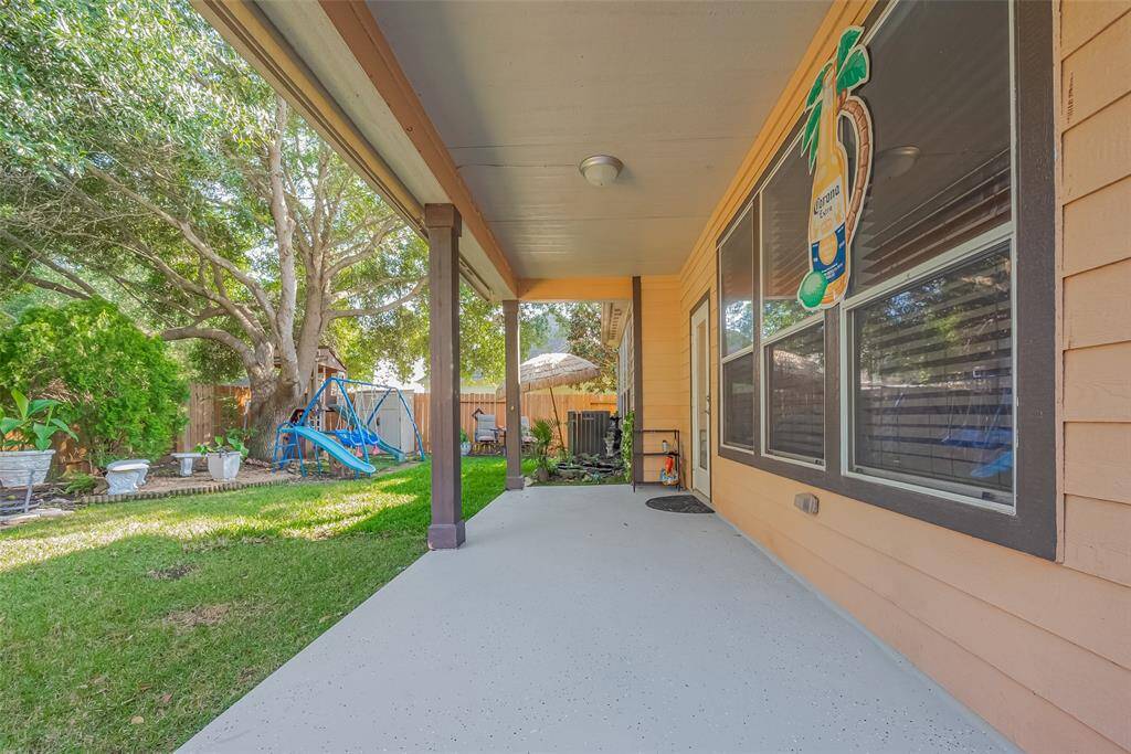 Huge  patio with rolling shades and sleek epoxy floors enhances the backyard's charm.