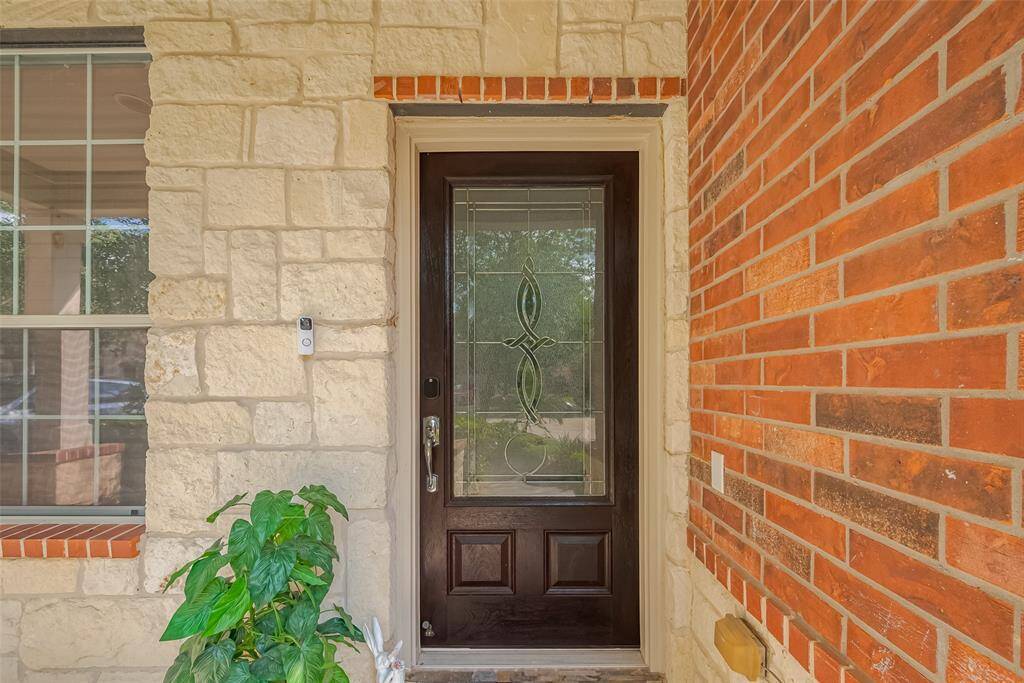 Inviting front entry with an elegant glass door and modern doorbell camera for added security.