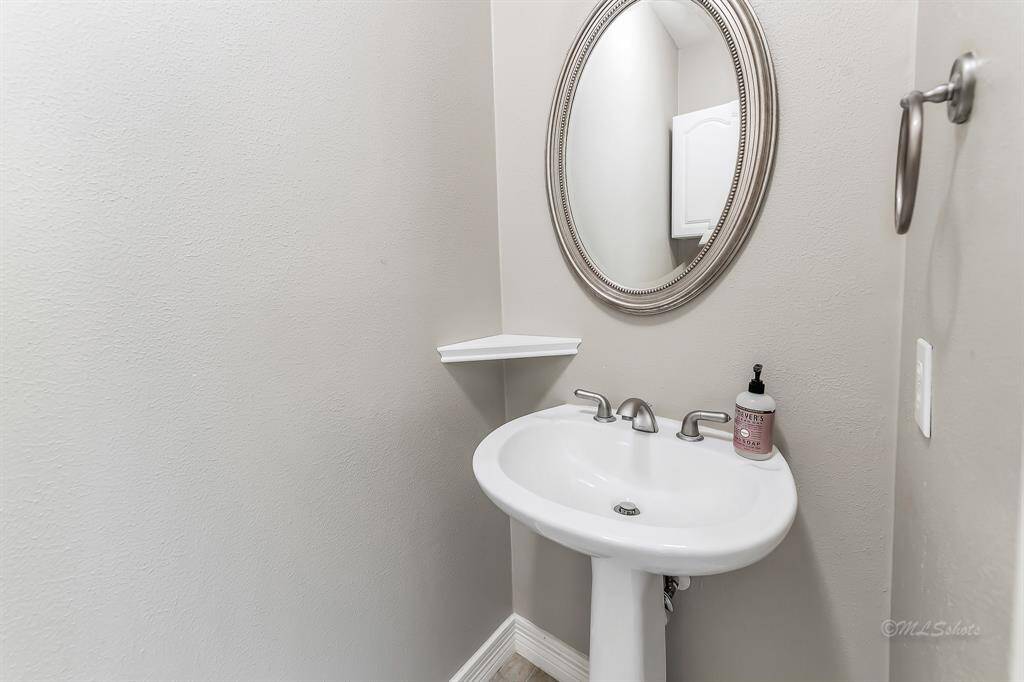 The powder room is tucked behind the kitchen and near the dining room.  It features nickel finishes, neutral paint, and storage cabinets.