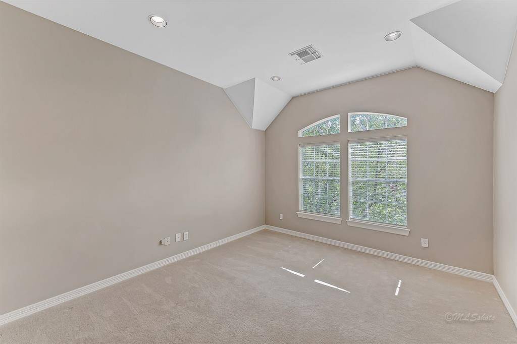 The space features neutral paint, vaulted ceilings, recessed lighting, bright windows, and plenty of room for a large sectional or office furniture.